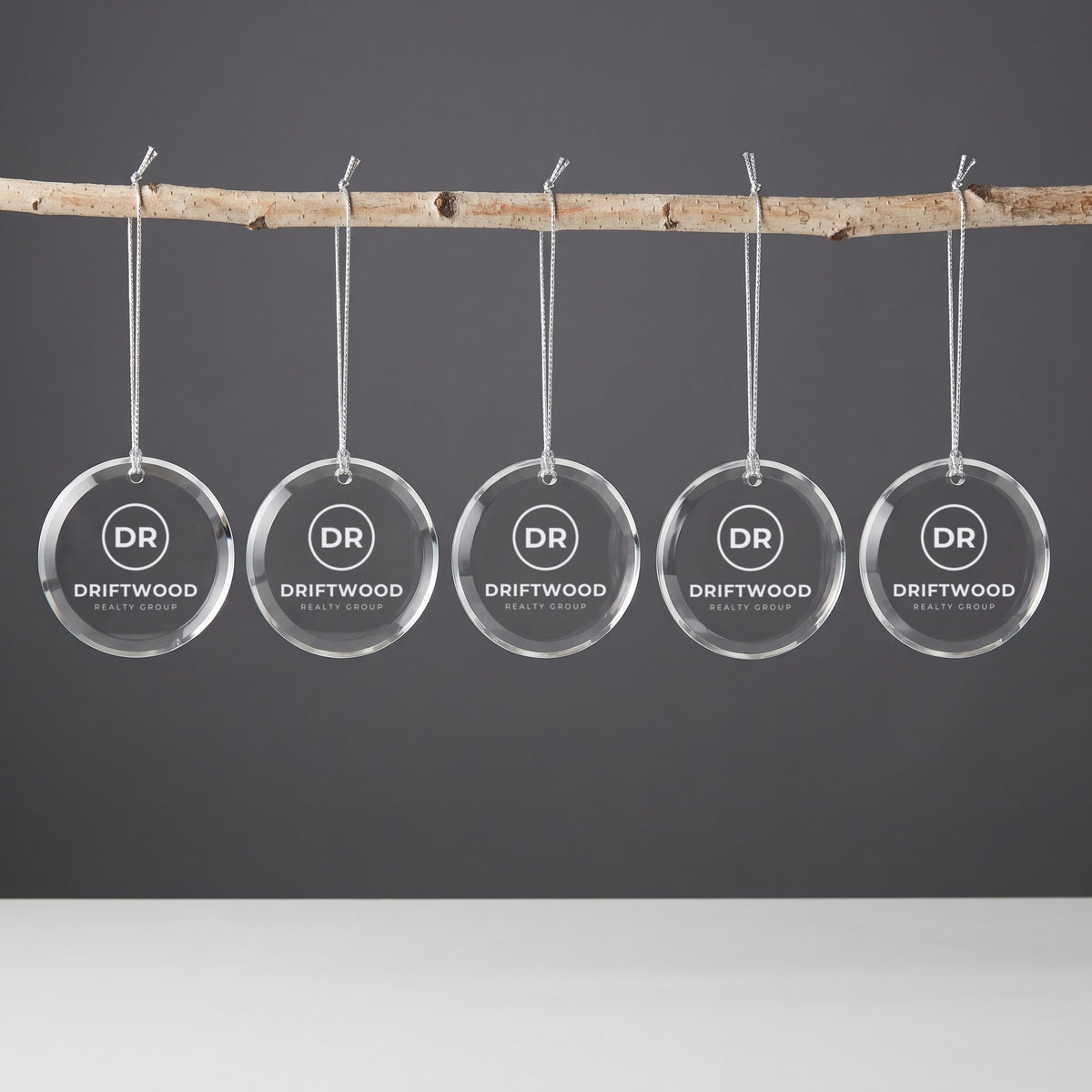 Custom Logo Glass Christmas Ornaments – five round ornaments hanging in a row, engraved with the same sample realty logo