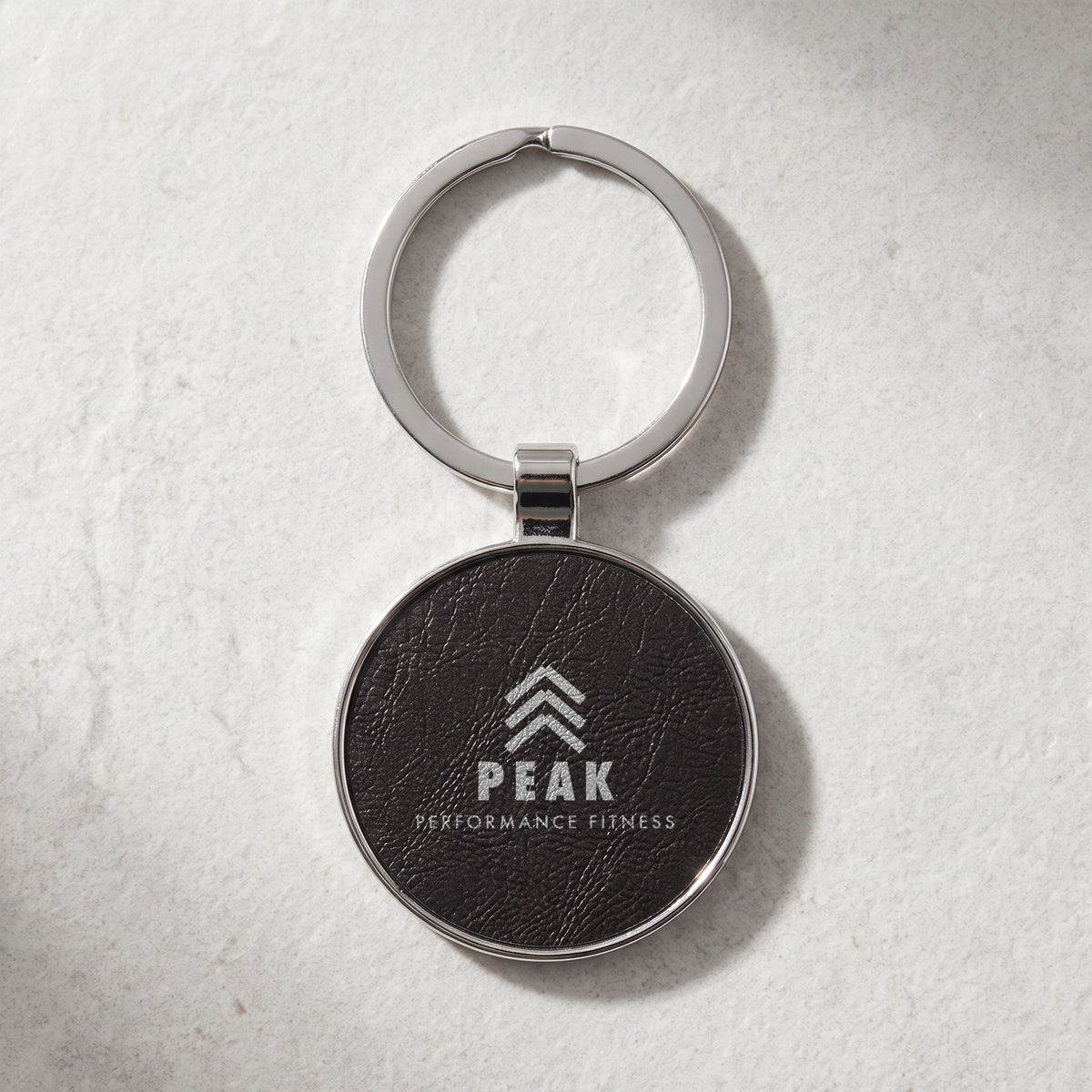 Custom Logo Leatherette & Metal Keychain – Round, Black/Silver with an engraved sample logo