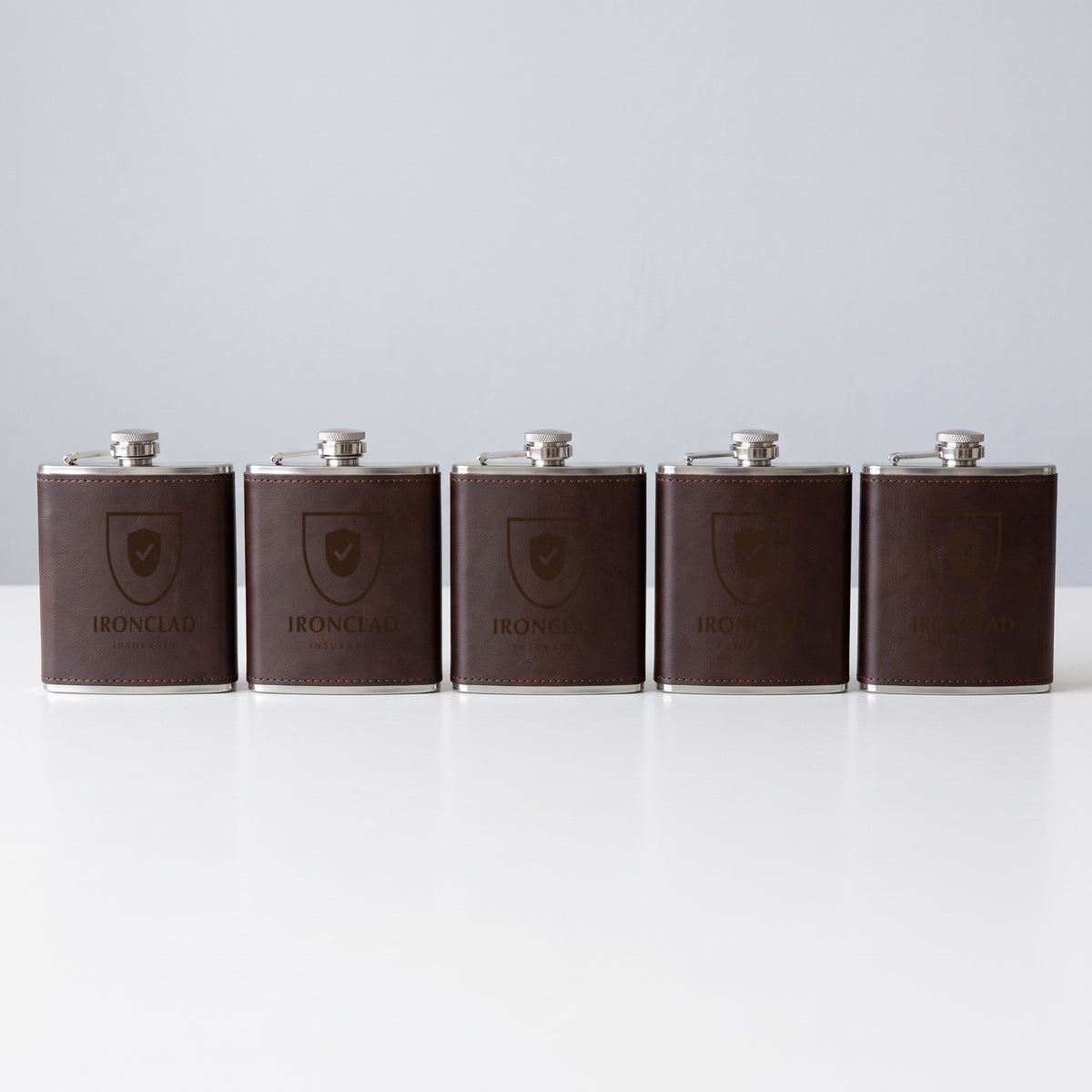 Custom Logo 6 oz Leatherette Flask – five dark brown flasks in bulk, engraved with the same sample logo