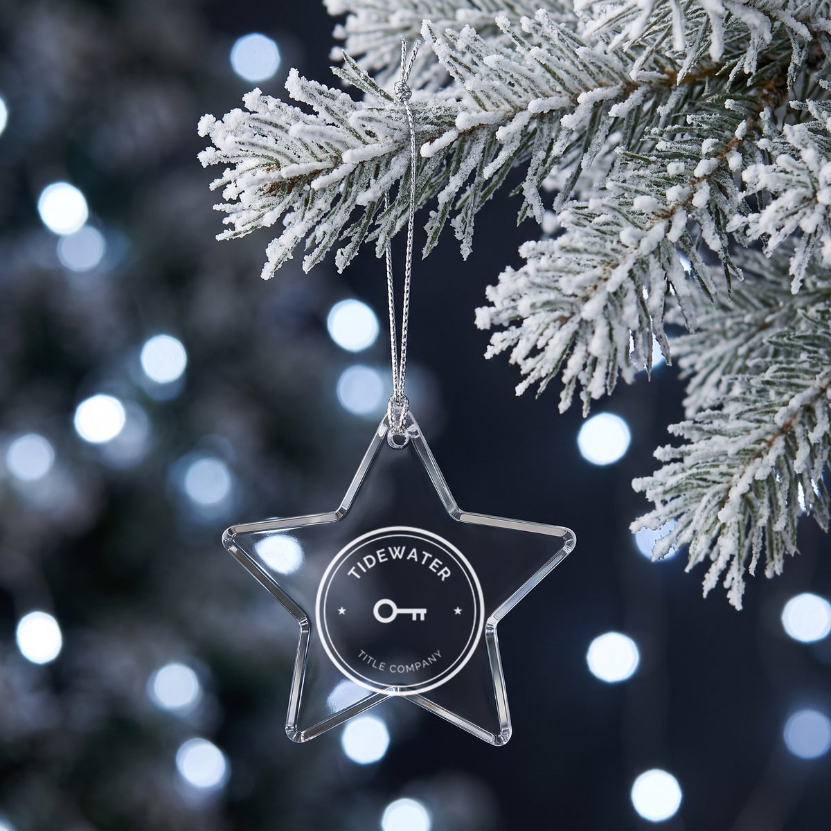 Custom Logo Glass Christmas Ornament, star shape with an engraved sample solar company logo on a snowy branch