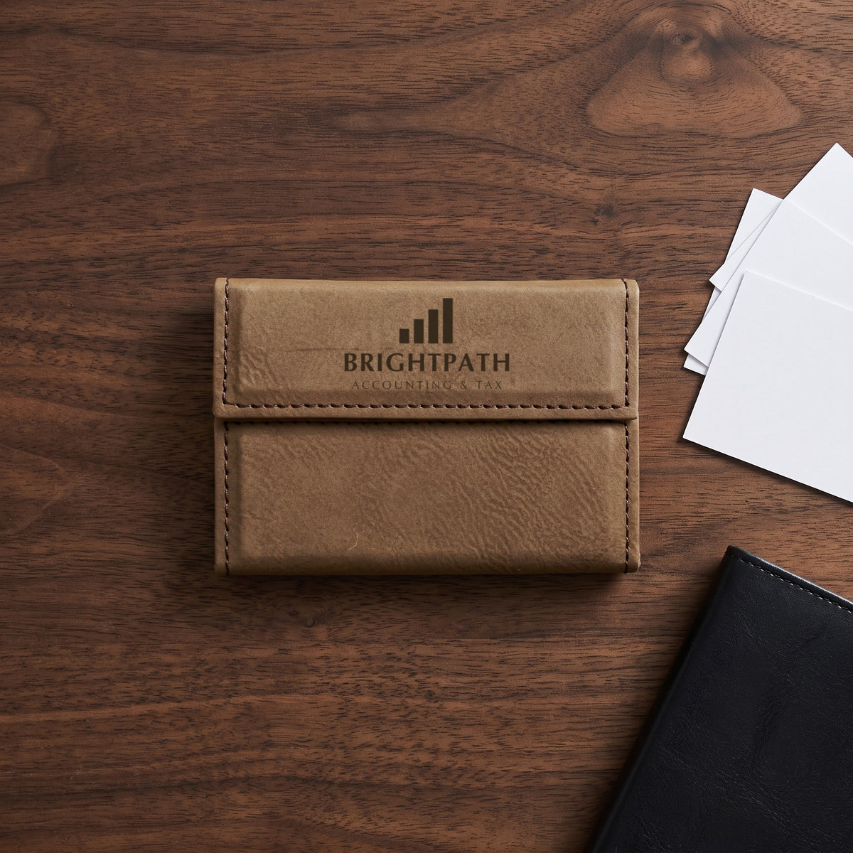 Custom Logo Leatherette Business Card Holder – Dark Brown on a walnut desk beside business cards, engraved sample logo