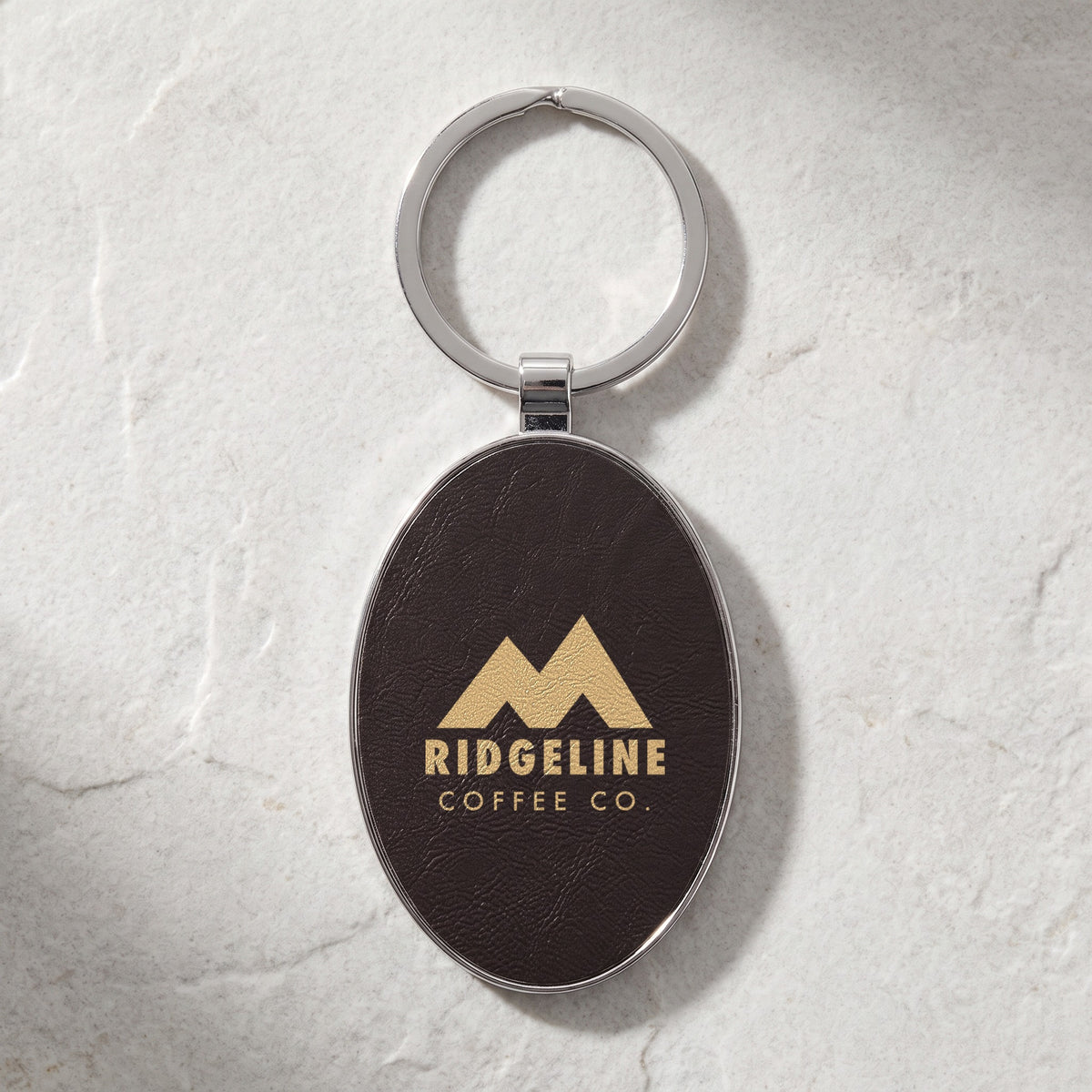 Custom Logo Leatherette & Metal Keychain – Oval, Black/Gold with an engraved sample logo