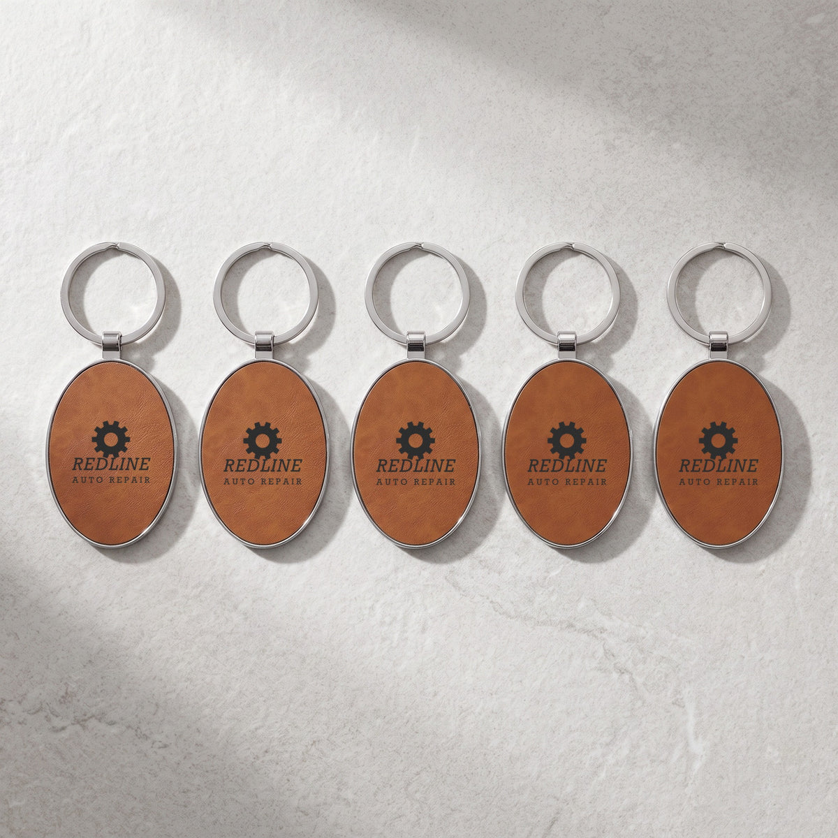 Custom Logo Leatherette & Metal Keychain – Oval – bulk order of Rawhide keychains, all engraved with the same sample logo