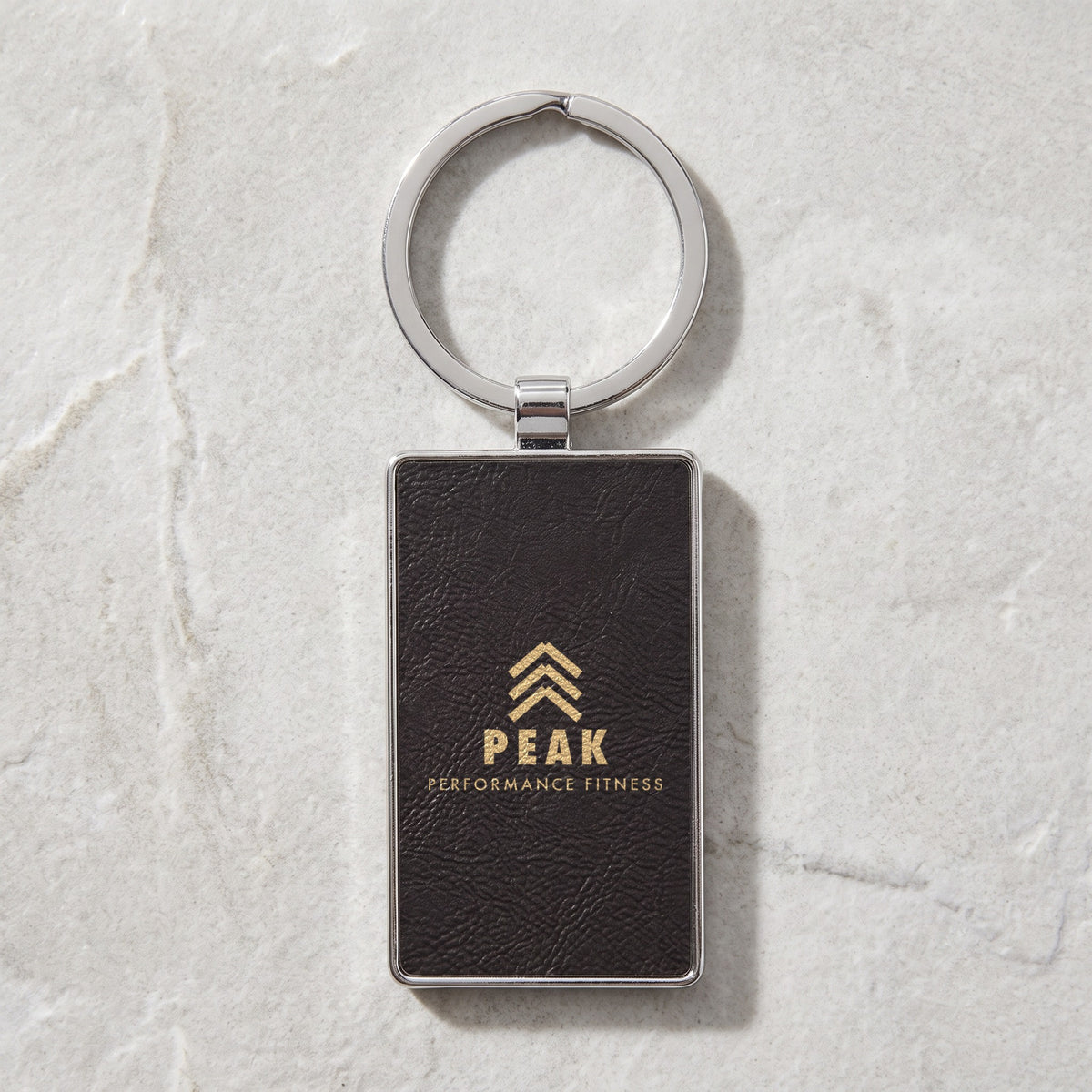 Custom Logo Leatherette & Metal Keychain – Rectangle, Black/Gold with an engraved sample logo