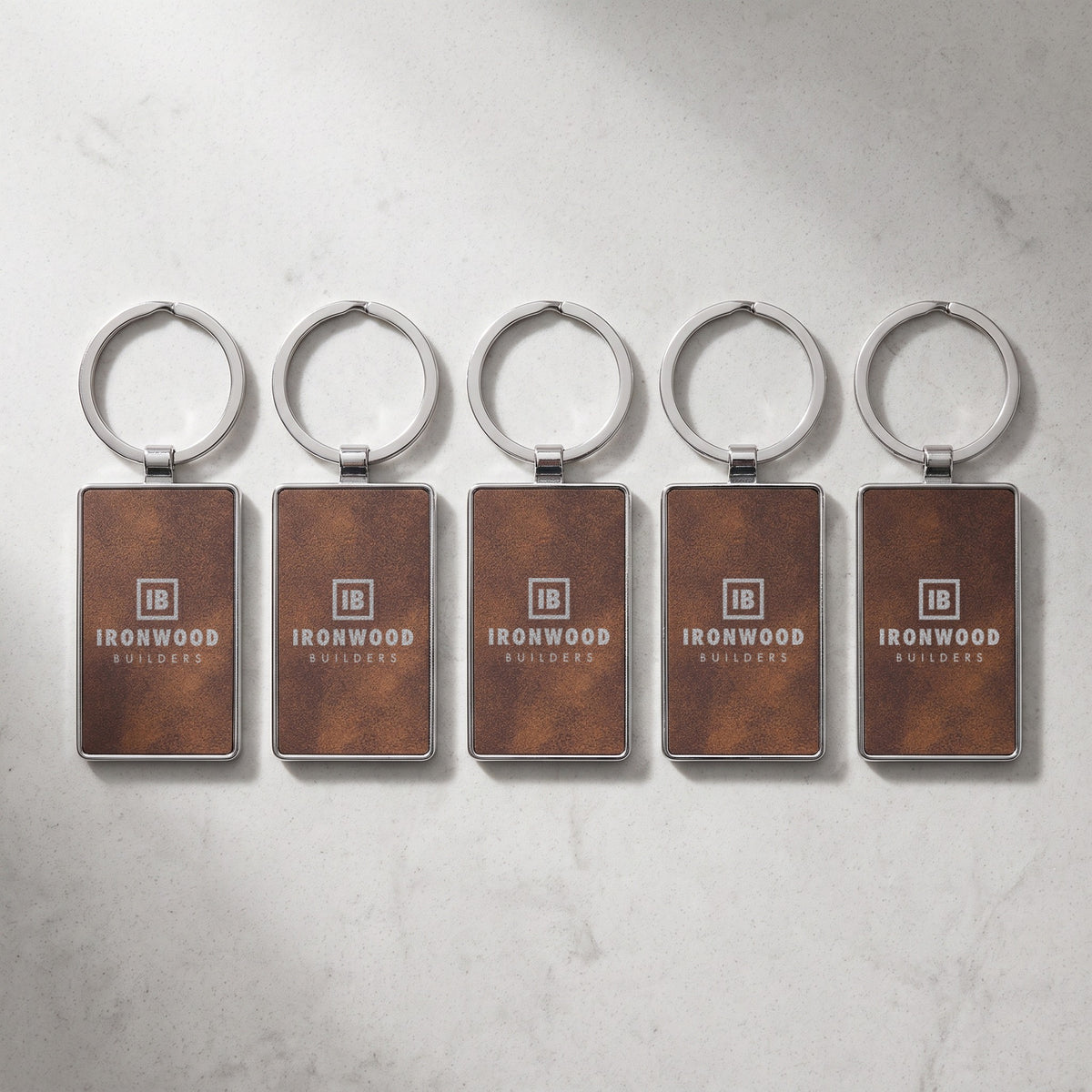 Custom Logo Leatherette & Metal Keychain – Rectangle – bulk order of Rustic/Silver keychains, all engraved with the same sample logo