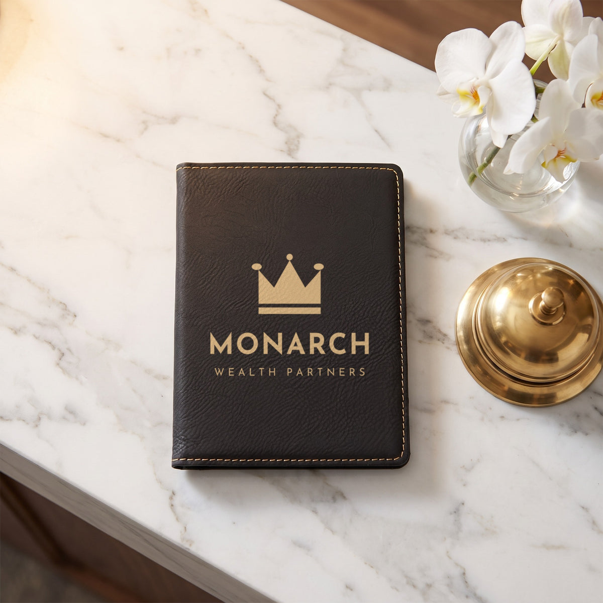 Custom Logo Leatherette Passport Holder, black/gold with a gold engraved sample logo on a hotel front desk