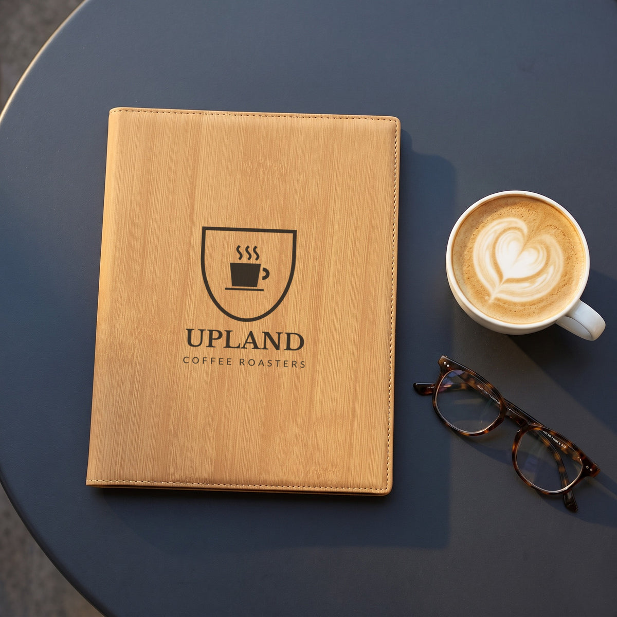 Custom Logo Leatherette Portfolio, bamboo with an engraved sample logo on a cafe table