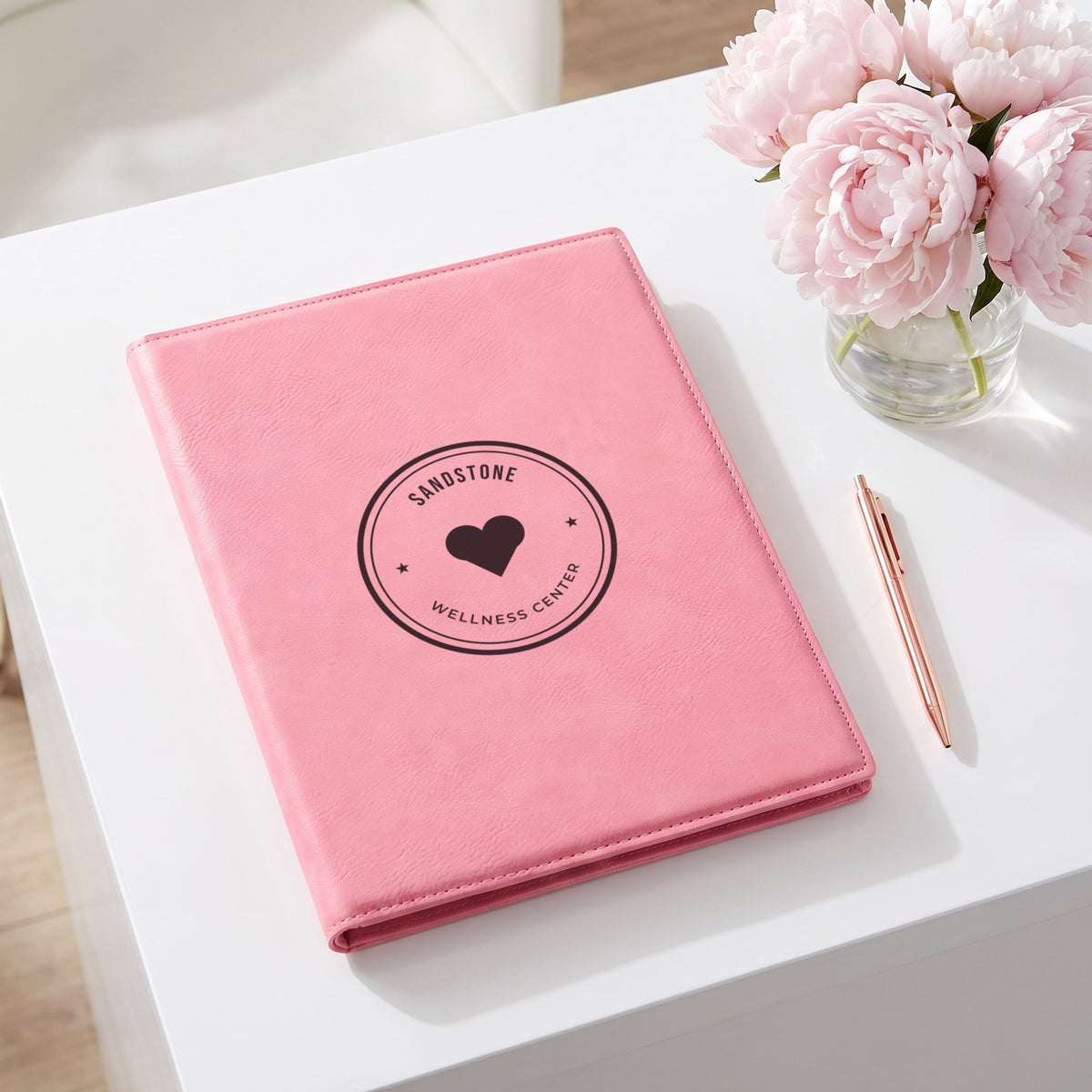 Custom Logo Leatherette Portfolio, pink with an engraved sample logo at a salon reception