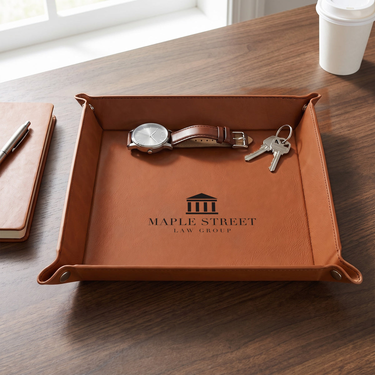 Custom Logo Leatherette Valet Tray – 9" Rawhide on an office desk holding a watch and keys, dark engraved sample logo