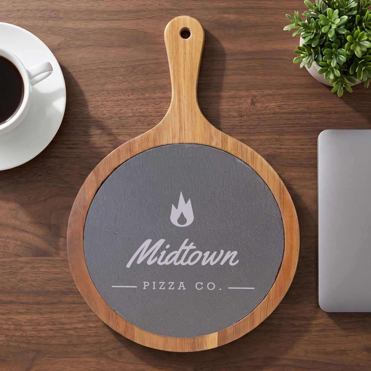 Custom Logo Round Slate & Acacia Serving Board with Handle, 8 1/4 inch board with an engraved sample logo on an office desk as a client gift