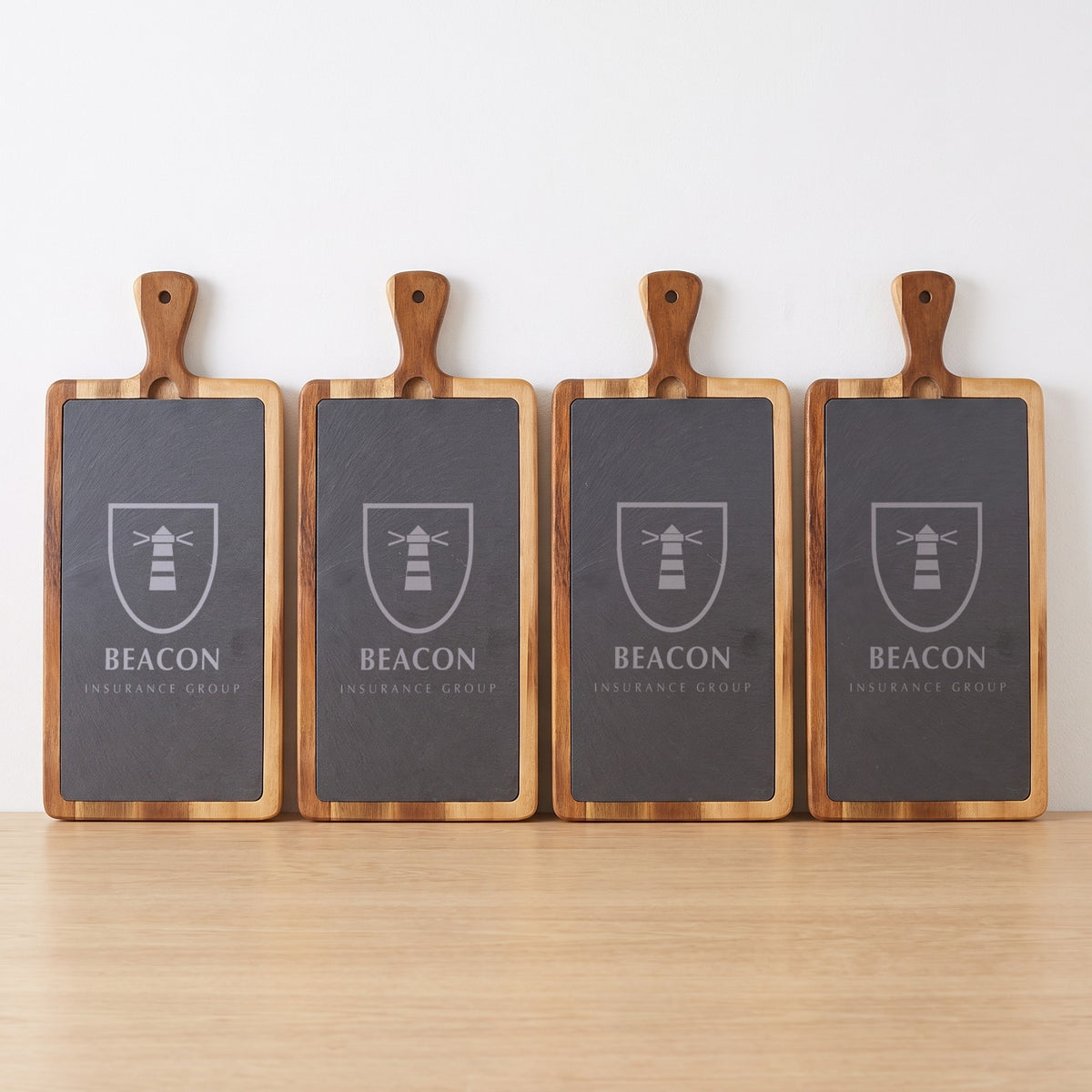 Custom Logo Slate & Acacia Paddle Cutting Board – a row of boards in bulk, engraved with the same sample logo