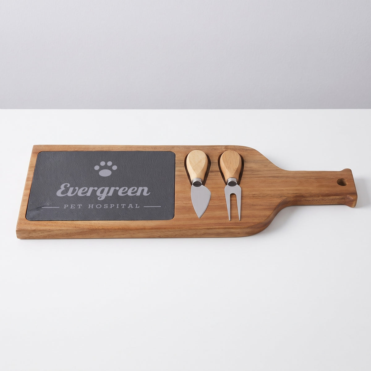 Custom Logo Slate & Acacia Serving Board, wine bottle board with an engraved sample logo on a plain table