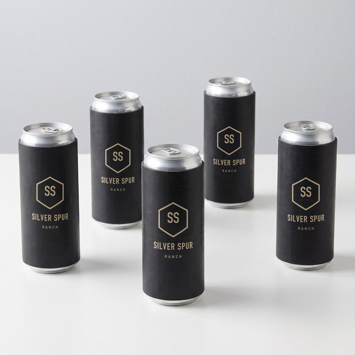 Custom Logo Leatherette Slim Can Coolers – five black/gold slim can coolers in bulk with gold engraved sample logos