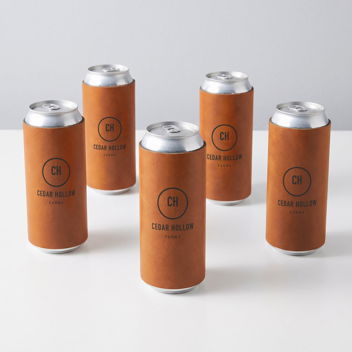 Custom Logo Leatherette Slim Can Coolers – five rawhide slim can coolers in bulk, engraved with the same sample logo